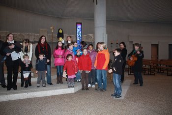 Ökumenischer Minigottesdienst Kinder stehen mit ihren Eltern im Altarraum einer modernen Kirche, feiern Gottesdienst und singen gemeinsam ein Lied